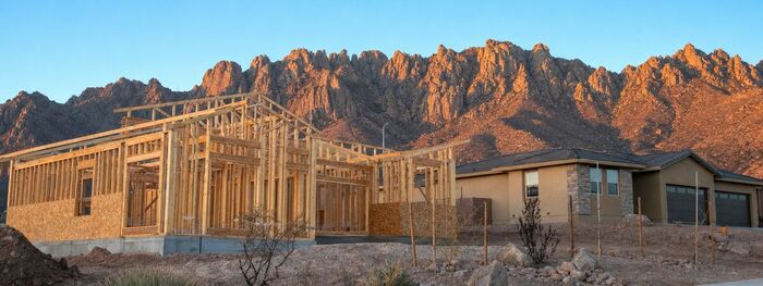 New home being framed next to a finished model home