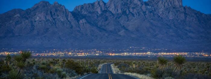 Desert highway leading toward the mountains at blue hour